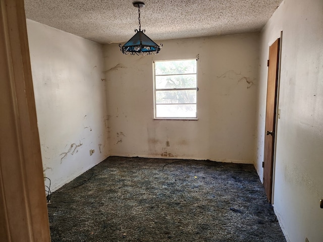 spare room with dark colored carpet and a textured ceiling