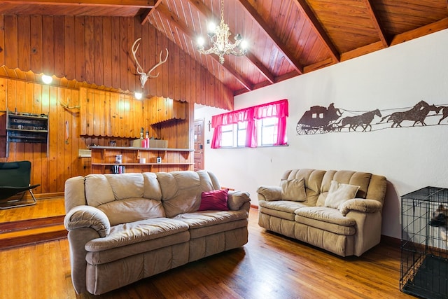 living area with beam ceiling, a notable chandelier, wood finished floors, wood walls, and wood ceiling