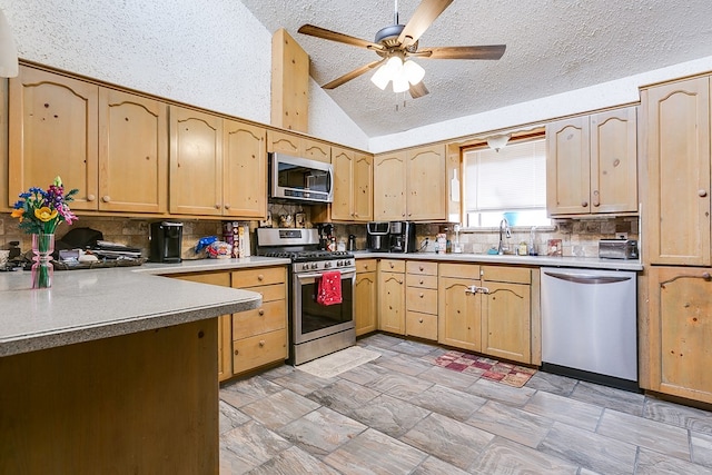 kitchen featuring tasteful backsplash, light brown cabinets, vaulted ceiling, stainless steel appliances, and a sink