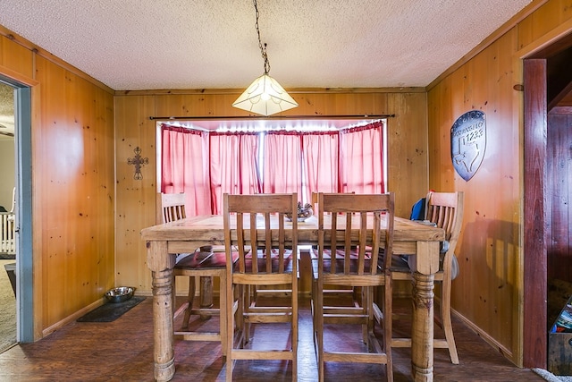 dining room featuring baseboards, wood walls, and a textured ceiling