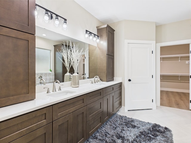 bathroom with double vanity, a sink, and a walk in closet