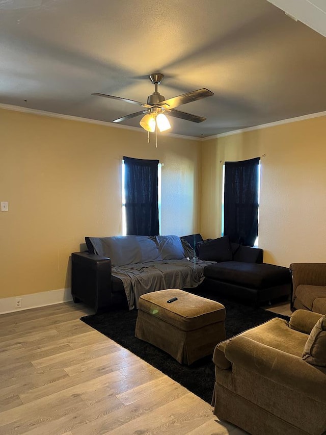 living area with baseboards, crown molding, ceiling fan, and wood finished floors