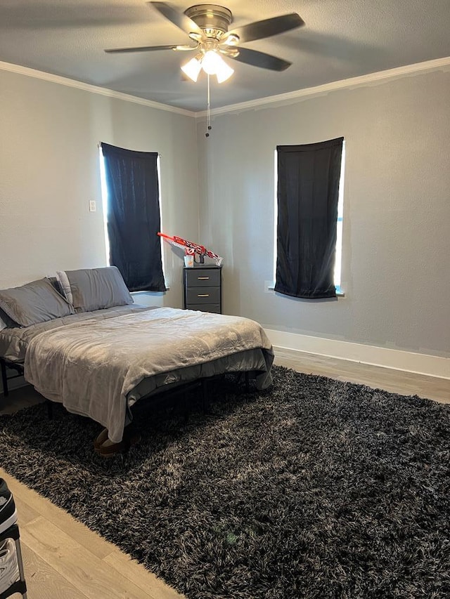 bedroom featuring crown molding, wood finished floors, baseboards, and ceiling fan