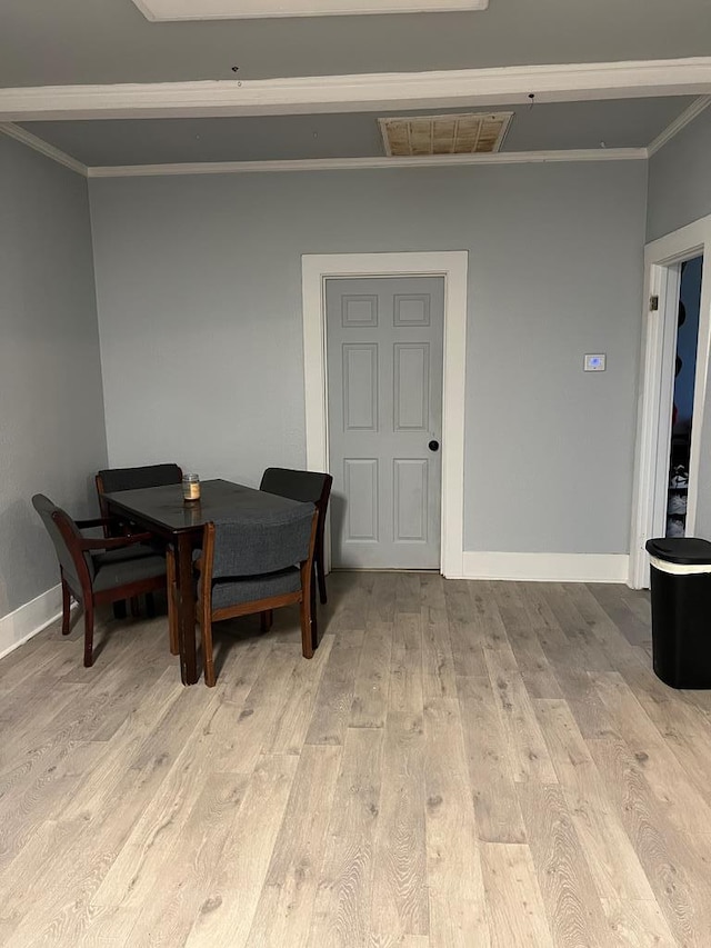 dining space with visible vents, baseboards, crown molding, and light wood finished floors