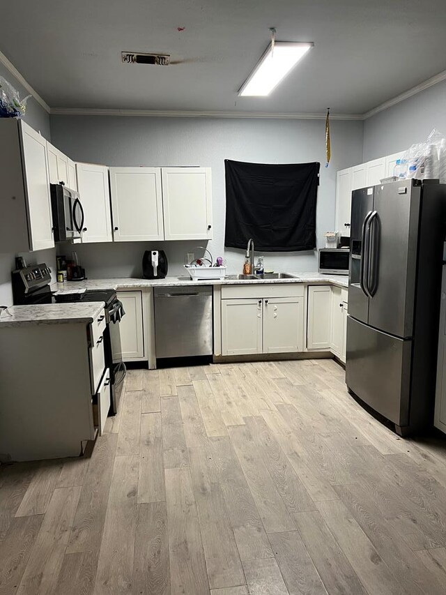 kitchen featuring visible vents, ornamental molding, a sink, light countertops, and appliances with stainless steel finishes