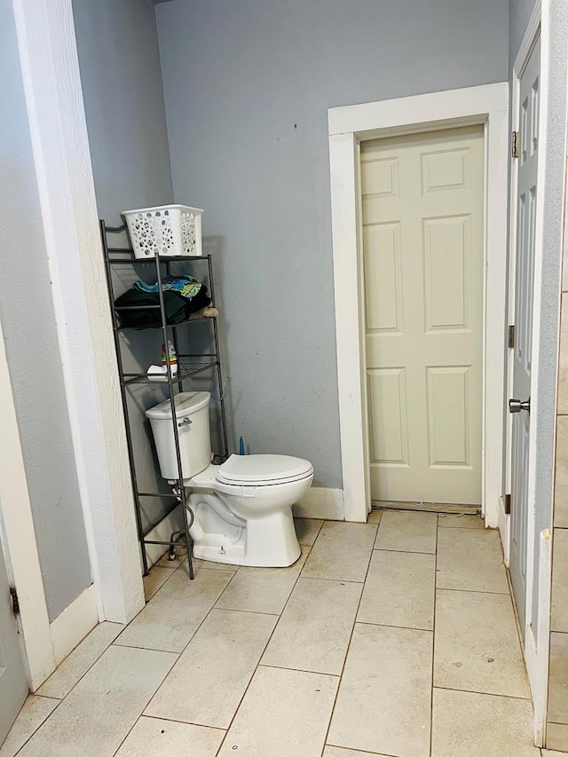 bathroom with tile patterned floors, toilet, and baseboards