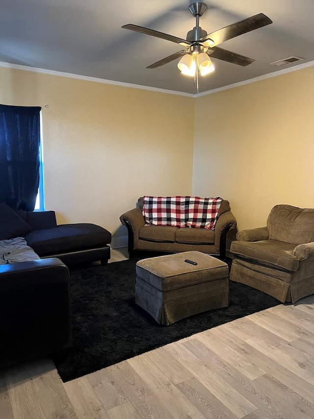 living room featuring visible vents, a ceiling fan, wood finished floors, and crown molding