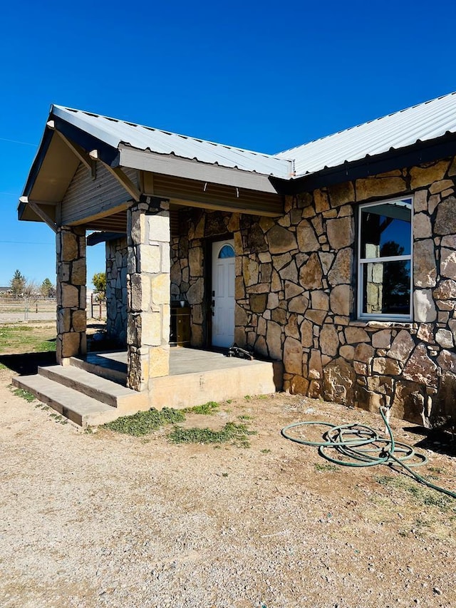 view of exterior entry featuring metal roof and stone siding