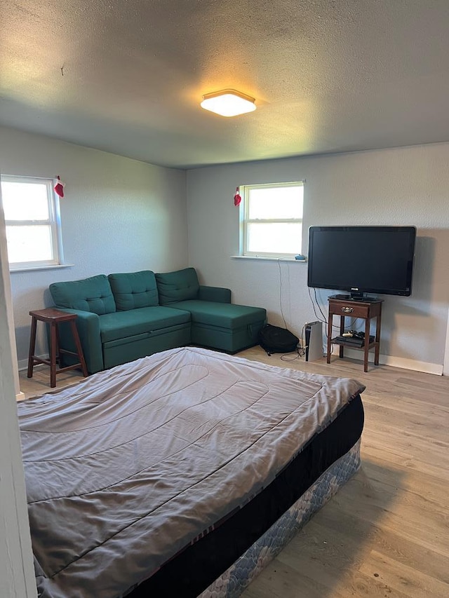 bedroom featuring wood finished floors, baseboards, and a textured ceiling