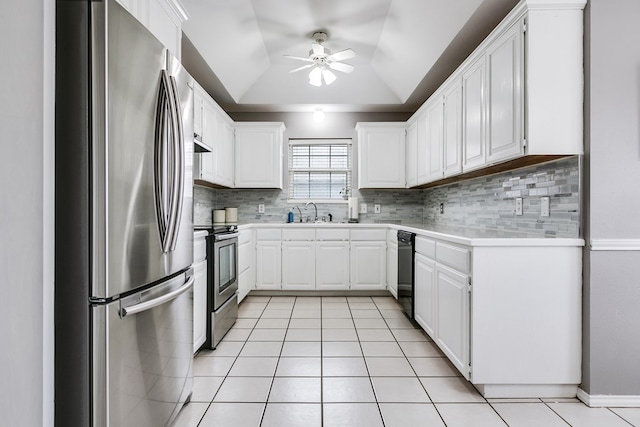 kitchen featuring sink, stainless steel appliances, a tray ceiling, white cabinets, and decorative backsplash