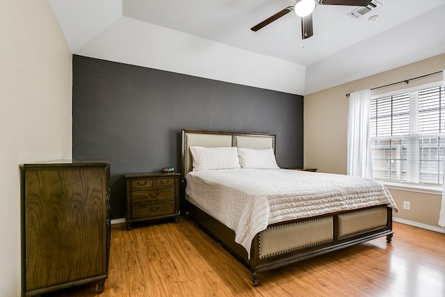 bedroom with ceiling fan, wood-type flooring, and a raised ceiling