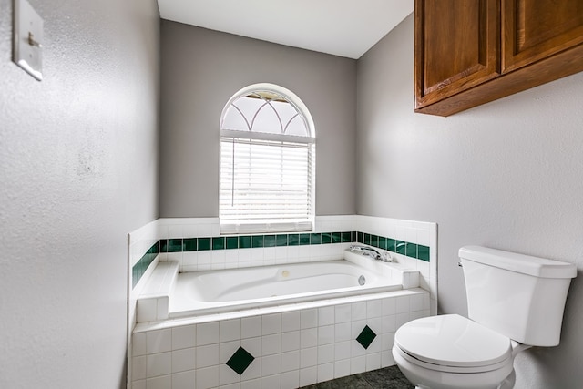 bathroom with tiled bath, tile patterned floors, and toilet