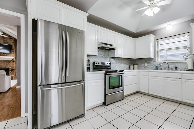 kitchen with lofted ceiling, sink, white cabinetry, stainless steel appliances, and light tile patterned flooring