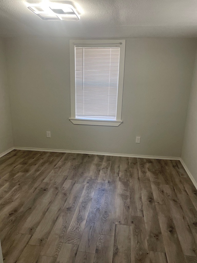 spare room featuring dark wood-type flooring and a textured ceiling