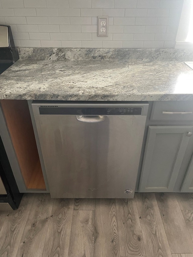 details featuring gray cabinets, stainless steel dishwasher, stone counters, and light hardwood / wood-style floors