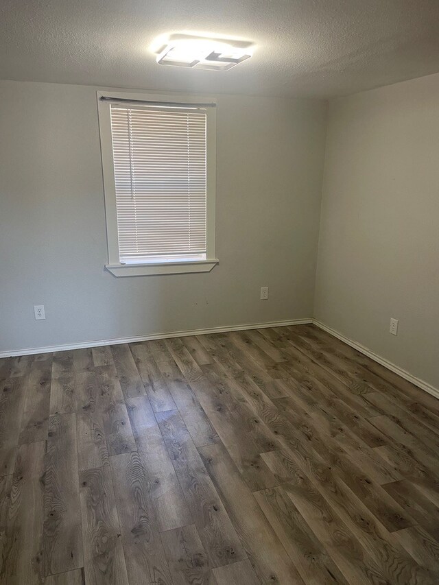 unfurnished room with dark wood-type flooring and a textured ceiling