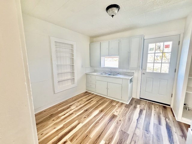 kitchen featuring sink, built in features, light hardwood / wood-style floors, and white cabinets