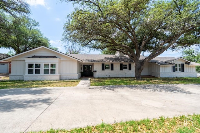 2301 Sul Ross St, San Angelo, TX 76904 - single story home with a chimney, a front lawn, board and batten siding, a shingled roof, and brick siding