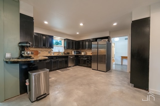 2301 Sul Ross St, San Angelo, TX 76904 - kitchen with dark cabinets, tasteful backsplash, stainless steel appliances, and finished concrete flooring
