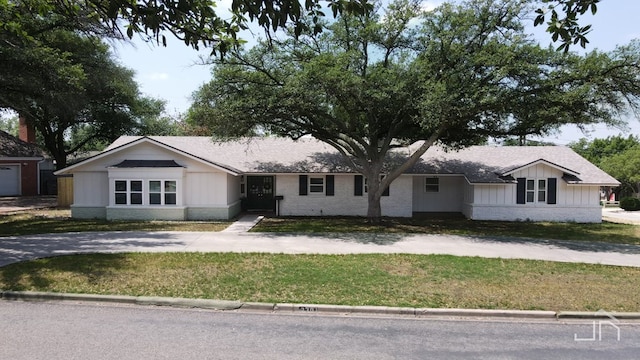 2301 Sul Ross St, San Angelo, TX 76904 - ranch-style house with roof with shingles, concrete driveway, brick siding, board and batten siding, and a front yard
