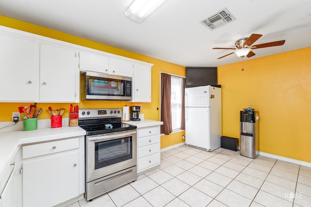 kitchen featuring light tile patterned flooring, appliances with stainless steel finishes, white cabinets, tile counters, and ceiling fan