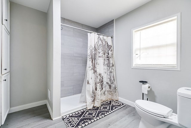full bathroom with a shower stall, toilet, wood finished floors, and baseboards