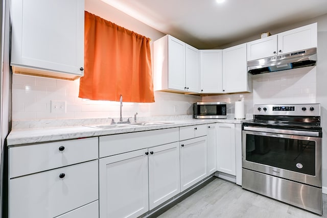 kitchen featuring a sink, appliances with stainless steel finishes, white cabinets, backsplash, and under cabinet range hood