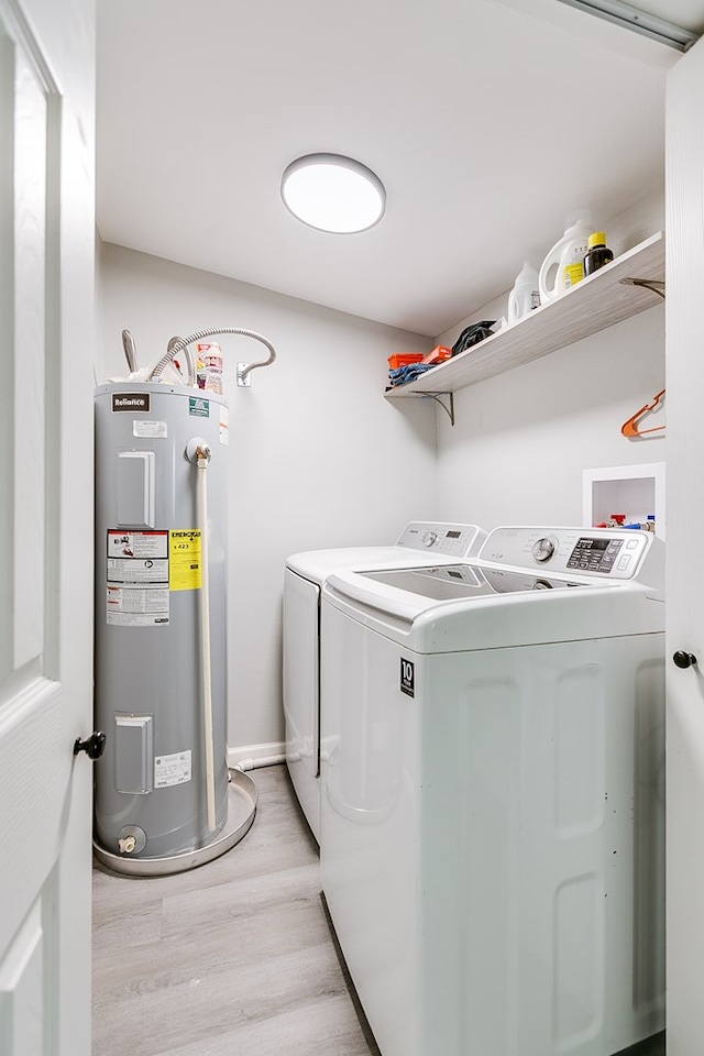 laundry area with water heater, washing machine and dryer, light wood-style flooring, and laundry area