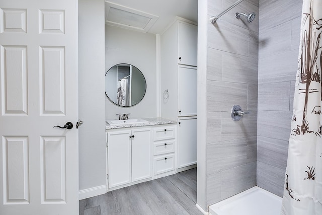 bathroom with a tile shower, vanity, and wood finished floors