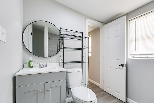 full bathroom with baseboards, wood finished floors, toilet, and vanity