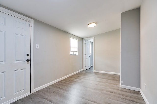 interior space featuring baseboards and light wood finished floors