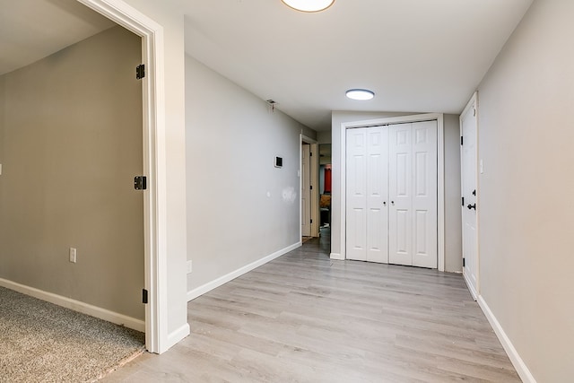 corridor with light wood finished floors and baseboards