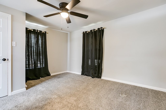 carpeted spare room featuring ceiling fan and baseboards