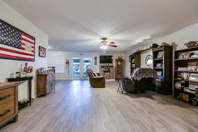 living room with ceiling fan, a fireplace, light hardwood / wood-style floors, and a textured ceiling