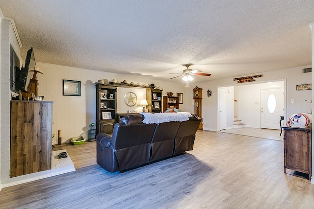 living room with ceiling fan, a textured ceiling, and light hardwood / wood-style floors