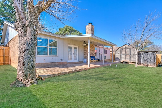 rear view of property featuring an outbuilding, a ceiling fan, fence, a storage unit, and french doors