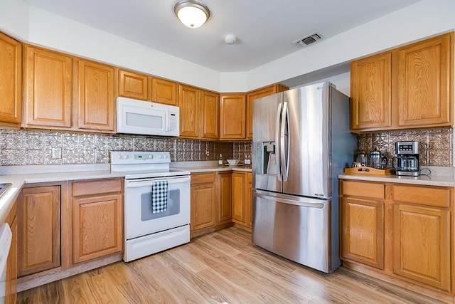 kitchen with white appliances, light countertops, light wood-type flooring, and brown cabinets