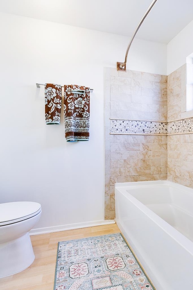 full bathroom featuring toilet, shower / tub combination, baseboards, and wood finished floors