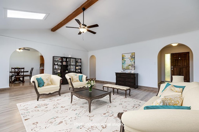 living room featuring arched walkways, vaulted ceiling with beams, and a ceiling fan