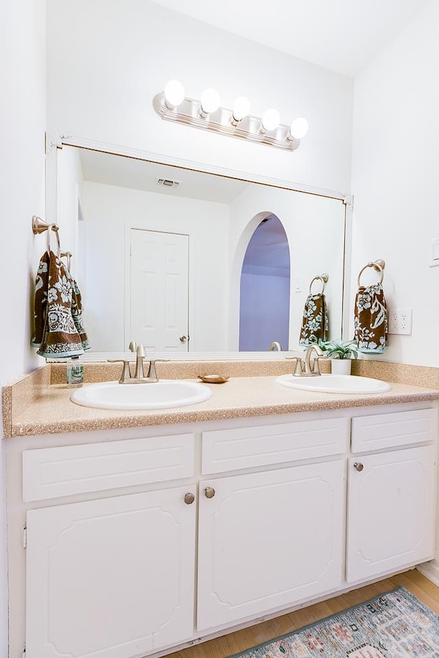 full bathroom featuring double vanity, visible vents, wood finished floors, and a sink