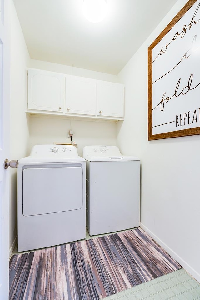 clothes washing area featuring baseboards, cabinet space, independent washer and dryer, and wood finished floors