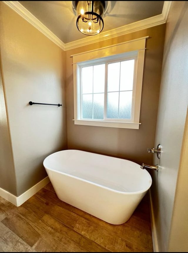 1958 Beaty Rd, San Angelo, TX 76904 - bathroom featuring crown molding, a freestanding bath, baseboards, wood finished floors, and a chandelier