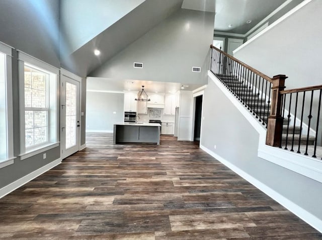 1958 Beaty Rd, San Angelo, TX 76904 - unfurnished living room with high vaulted ceiling, stairway, dark wood finished floors, baseboards, and a chandelier