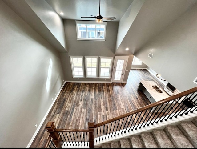 1958 Beaty Rd, San Angelo, TX 76904 - unfurnished living room featuring baseboards, ceiling fan, wood finished floors, a high ceiling, and stairway