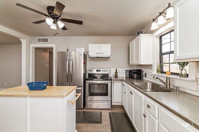 kitchen featuring visible vents, under cabinet range hood, stainless steel appliances, wood counters, and a sink