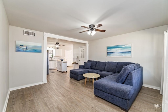 living room with visible vents, ceiling fan, baseboards, and light wood-style floors