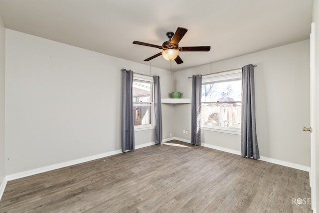 empty room featuring ceiling fan, baseboards, and wood finished floors