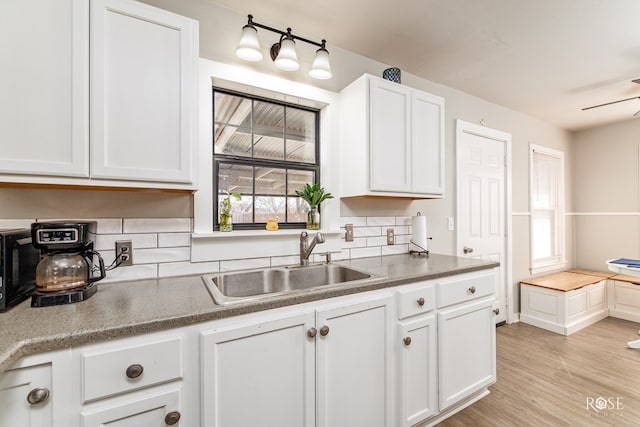 kitchen featuring white cabinets, a ceiling fan, light wood-type flooring, and a sink