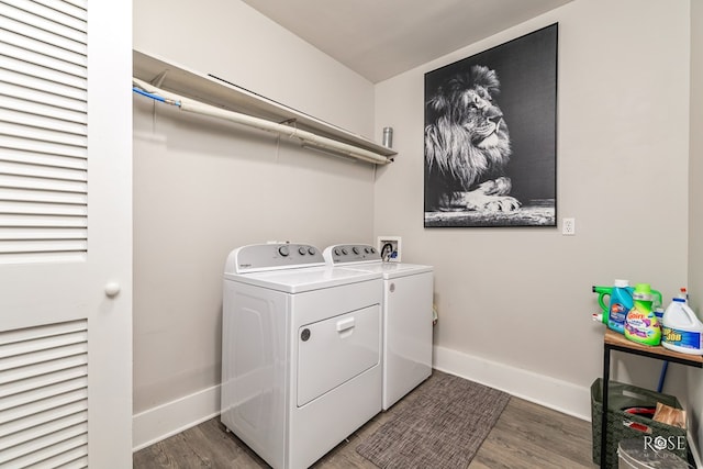 clothes washing area featuring laundry area, washing machine and dryer, baseboards, and wood finished floors