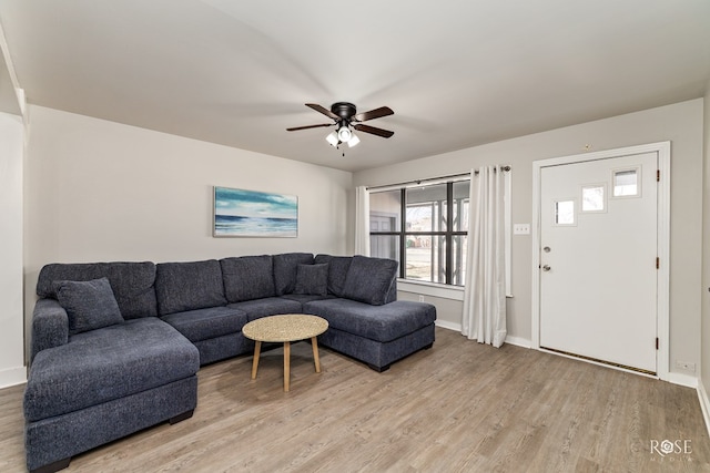 living area with baseboards, light wood-type flooring, and ceiling fan